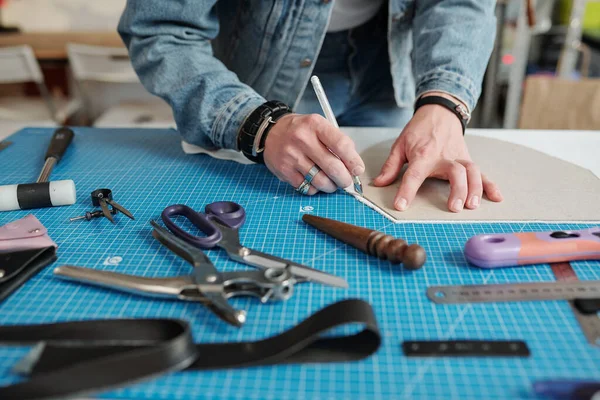 Manos Artesano Joven Inclinándose Sobre Mesa Mientras Delinea Patrón Papel — Foto de Stock