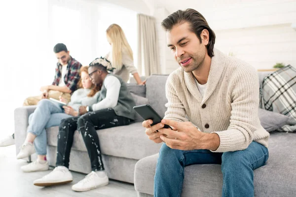 Hedendaagse Jonge Casual Man Scrollen Smartphone Terwijl Zitten Bank Achtergrond — Stockfoto