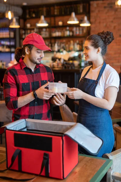 Junger Kurier Arbeitskleidung Nimmt Plastikbehälter Mit Lebensmitteln Aus Den Händen — Stockfoto