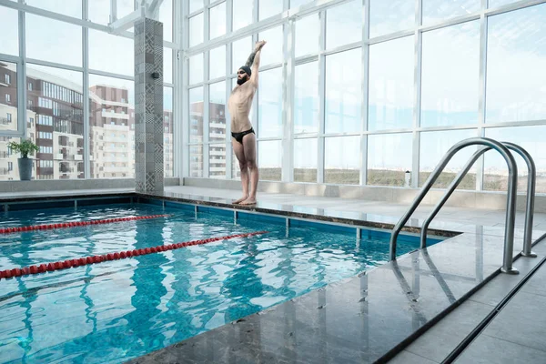 水泳の前にプールとストレッチ体の端に立って筋肉体を持つひげそりの水泳 — ストック写真