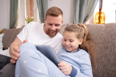 Mutlu genç adam ve dokunmatik yastıklı tatlı kızı online film izlerken gülüyorlar ve bunu ev ortamında tartışıyorlar.