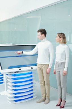 Bir tanesi takım çalışması sırasında interaktif görüntüye işaret ederken, iki zarif iş arkadaşı sanal bilgiyle çalışıyor.