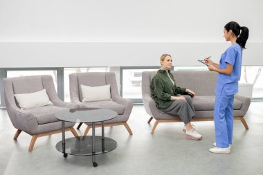 Tıbbi konsültasyondan önce mavi üniformalı güzel bir esmer asistan klinikteki hastalardan birinin adını yazıyor.