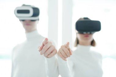 VR kulaklıklardaki fütürist uygulamaların ya da teknolojilerin iki genç geliştiricisinin elleri yeni yazılımı test ederken sanal görüntüyü gösteriyor