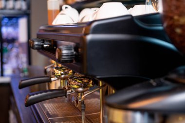 İki siyah plastik saplı modern kahve makinesi, üzerlerinde düğmeler ve cappuccino için beyaz porselen bardaklar.