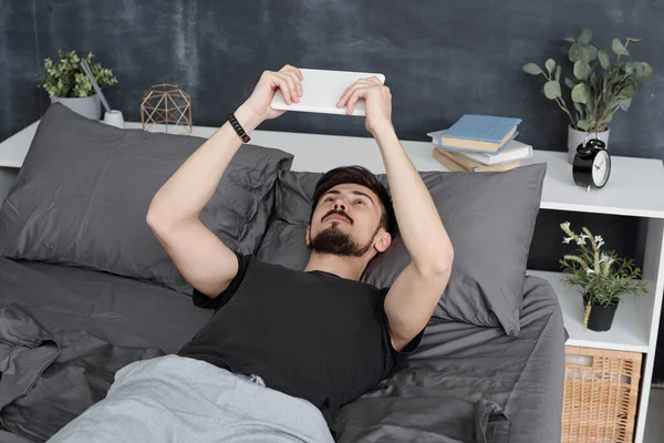 留胡子的男人躺在床上 用平板电脑 在检疫期间呆在家里 — 图库照片