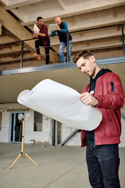 Joven Ingeniero Serio Arquitecto Mirando Boceto Plano Mientras Sus Dos — Foto de Stock