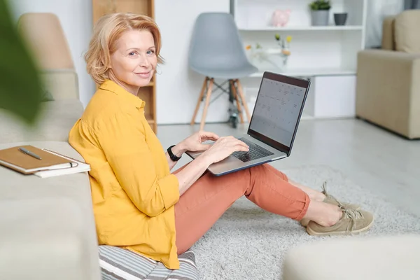 Happy Mature Blond Woman Laptop Her Knees Sitting Floor Carrying — Stock Photo, Image