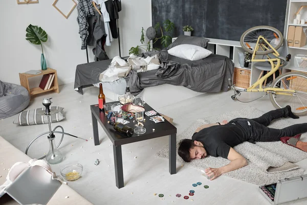 狂欢作乐的派对结束后 酒醉的醉汉在凌乱的公寓里 空着杯子睡在地板上 精疲力竭 — 图库照片