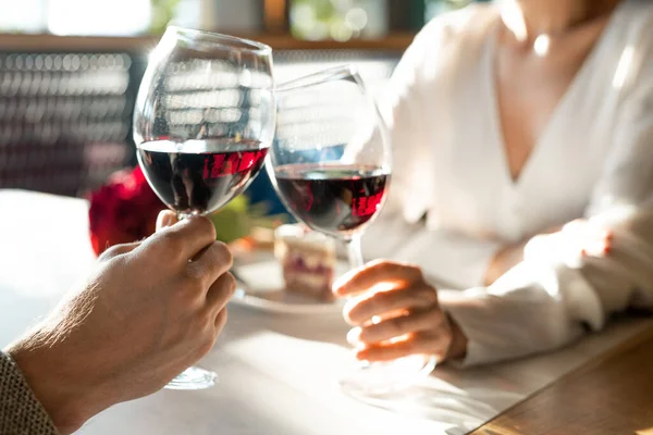 年轻人和他的女朋友在奢华的餐厅享受浪漫的约会和午餐时 手和酒杯在桌上碰了碰 — 图库照片
