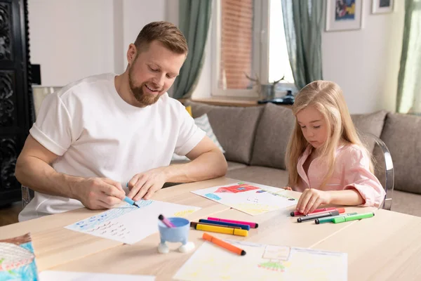 快乐的年轻人和他可爱的小女儿坐在客厅里的木桌边 画着画布 — 图库照片
