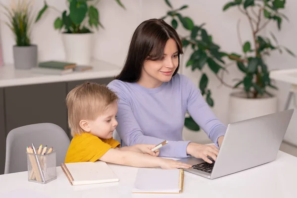 Roztomilý Syn Sedí Stolu Dotýká Matky Notebook Zatímco Pomáhá Prací — Stock fotografie