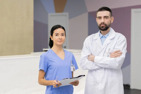 Hezká Mladá Asistentka Modré Uniformě Sebevědomý Zubař Whitecoat Stojící Před — Stock fotografie