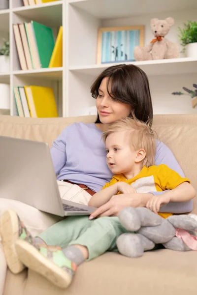 Blond Haired Boy Embraced Mom Sitting Sofa Watching Curious Cartoon — Stock Photo, Image