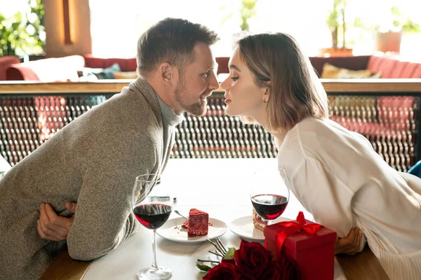 在餐馆举行的浪漫约会中 快乐而又深情的年轻夫妇弯腰坐在餐桌前 面面相觑 — 图库照片