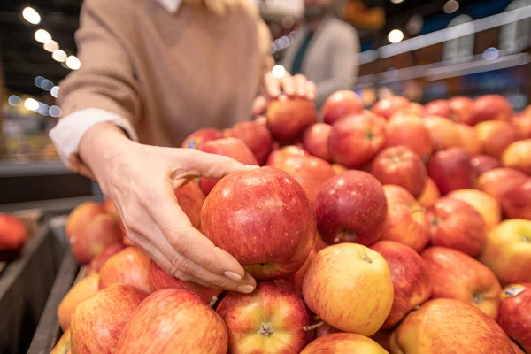 在超市与丈夫购买食品时 由成熟的女性顾客亲手挑选新鲜的红色苹果在水果展示会上展出 — 图库照片