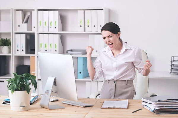 年轻快乐的女商人或女经纪人站在办公室电脑显示器前表达胜利 — 图库照片