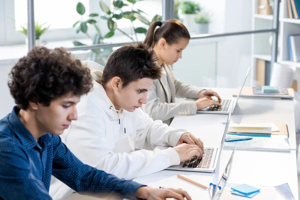 Grupo Três Adolescentes Estudantes Sentados Fila Por Mesa Olhando Para — Fotografia de Stock