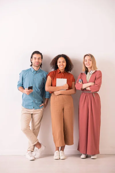 Retrato Alegres Amigos Multiétnicos Modernos Sosteniendo Gadgets Pie Contra Pared — Foto de Stock