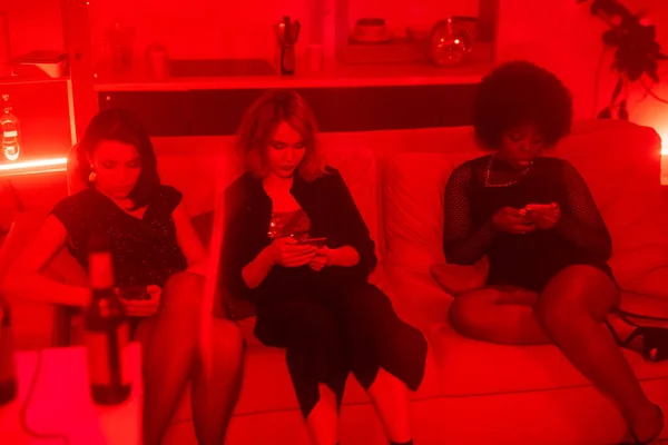 Rij Van Drie Interculturele Meisjes Glamoureuze Jurken Scrollen Smartphones Terwijl — Stockfoto