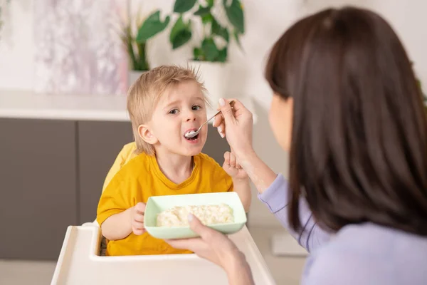 Sopra Vista Spalla Figlio Nutrente Madre Con Porridge Usando Cucchiaio — Foto Stock