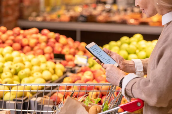 Współczesna Dojrzała Kobieta Klient Przewijając Listę Produktów Spożywczych Zakupu Supermarkecie — Zdjęcie stockowe