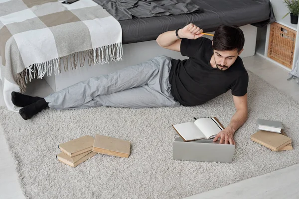 Jovem Estudante Pensativo Roupa Casa Deitado Entre Livros Tapete Analisando — Fotografia de Stock