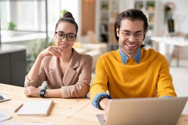 Jóvenes Colegas Negocios Positivos Anteojos Sentados Mesa Utilizando Portátil Mientras — Foto de Stock