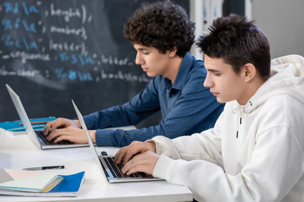 Dois Rapazes Adolescentes Digitando Frente Laptops Enquanto Sentado Por Mesa — Fotografia de Stock