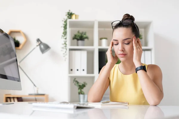 Trött Ung Affärskvinna Med Glasögon Huvudet Sitter Vid Skrivbordet Kontoret — Stockfoto