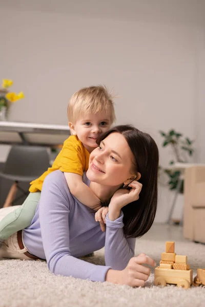 Cute Little Boy Embracing His Cheerful Mother While Both Lying — Stock Photo, Image