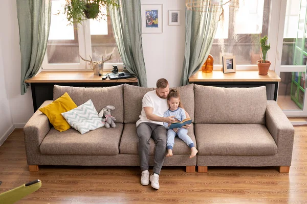 Young Father His Cute Little Daughter Sitting Couch Reading Book — Stock Photo, Image