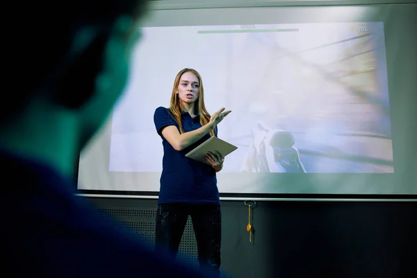 自信的女性游戏开发者在投影屏幕上演示新网络游戏时使用平板电脑 — 图库照片