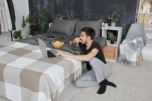 Jovem Roupa Casa Sentado Chão Quarto Usando Laptop Enquanto Come — Fotografia de Stock