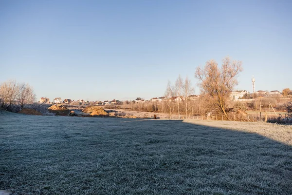 A plot of land with a lawn for the construction of a house or territory for grazing farm animals in frosty sunny morning