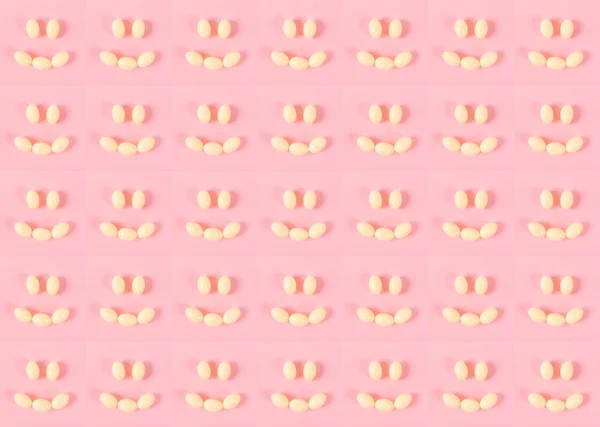 Padrão de muitos pequenos sorrisos feitos de pílulas ou ovos em um fundo rosa. Emoções felizes . — Fotografia de Stock