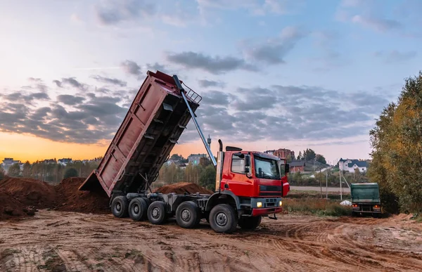 Bir çöp kamyonu kazı alanına çakıl döküyor.