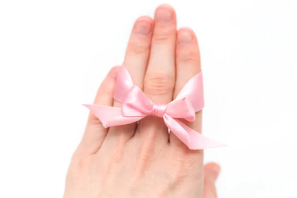 Uma pulseira de arco rosa está em uma palma em um fundo branco. Símbolo da identidade sexual da menina . — Fotografia de Stock