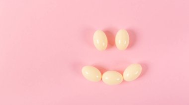 Gülümseme şeklinde pembe bir arka planda hapların ve kapsüllerin bileşimi. Mutlu duygular. Psikolojik yardım.