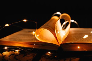 Parlak çelenk ışıklarıyla süslenmiş kalp şeklinde çarşafları olan sanat kitabı. Aşkın sembolü.