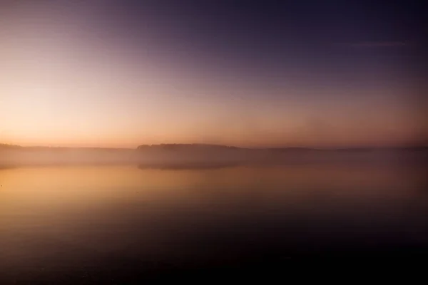 Temprano en la mañana en el lago con un amanecer rosado y neblina envuelta de niebla, un místico hipnotizante de la naturaleza — Foto de Stock