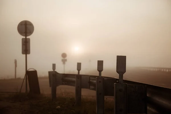 Lever de soleil et brouillard sur la piste, au loin, vous pouvez voir les phares d'une voiture qui passe — Photo