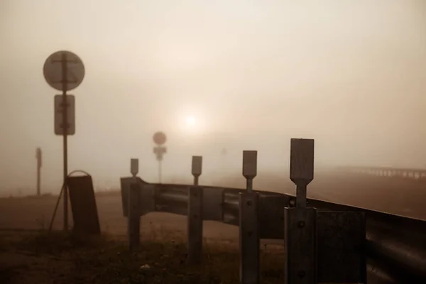 Wschód słońca i mgła na torze, w oddali widać reflektory przejeżdżającego samochodu — Zdjęcie stockowe
