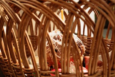 Paskalya samanı sepeti Paskalya pastası, parlak süslü yumurtalar ve yanan bir kilise mumuyla süslenmiş şenlikli bir peçeteyle süslenmiş. Neşeli bir ikram ve huzurlu bir ruh hali..