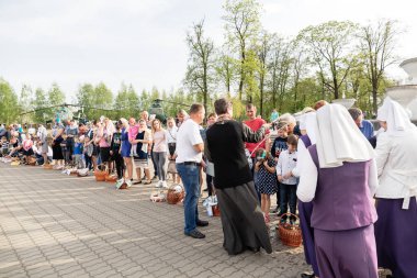 Beryoza, Belarus - 27 Nisan 2019: Rahip, Hristiyan dini geleneklerine göre, inançlıları ve Paskalya pastalarını, yumurta ve mumları kilisenin yakınında kutsal suyla boyadı..