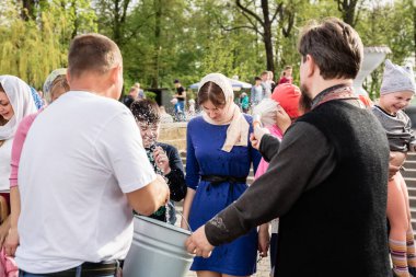 Beryoza, Belarus - 27 Nisan 2019: Rahip, Hristiyan dini geleneklerine göre, inançlıları ve Paskalya pastalarını, yumurta ve mumları kilisenin yakınında kutsal suyla boyadı..