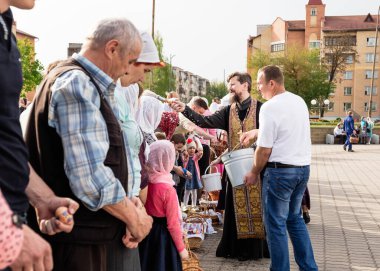 Beryoza, Belarus - 27 Nisan 2019: Rahip, Hristiyan dini geleneklerine göre, inançlıları ve Paskalya pastalarını, yumurta ve mumları kilisenin yakınında kutsal suyla boyadı..