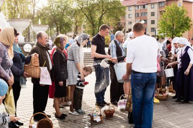Beryoza, Belarus - 27 Nisan 2019: Rahip, Hristiyan dini geleneklerine göre, inançlıları ve Paskalya pastalarını, yumurta ve mumları kilisenin yakınında kutsal suyla boyadı..