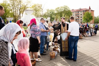 Beryoza, Belarus - 27 Nisan 2019: Rahip, Hristiyan dini geleneklerine göre, inançlıları ve Paskalya pastalarını, yumurta ve mumları kilisenin yakınında kutsal suyla boyadı..