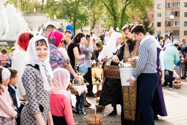 Beryoza, Belarus - 27 Nisan 2019: Rahip, Hristiyan dini geleneklerine göre, inançlıları ve Paskalya pastalarını, yumurta ve mumları kilisenin yakınında kutsal suyla boyadı..